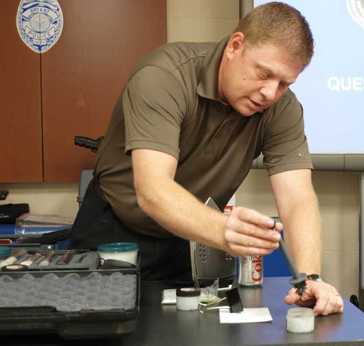 Corporal Detective Todd Crowson demonstrates the use of magnetic fingerprint powder.  The black powder can be cleaned up easily due to its magnetic properties. (Photo by Lana Clifton)