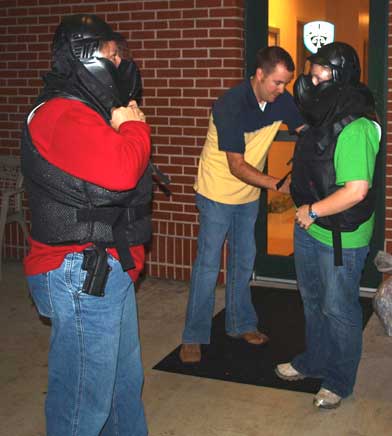 Bryant Police Department Detective Nick Ramsey assists Citizen’s Police Academy students Kim Wheelbarger and Christen Helton with their protective gear as they prepare for traffic stop simulations. (Photo by LANA CLIFTON)
