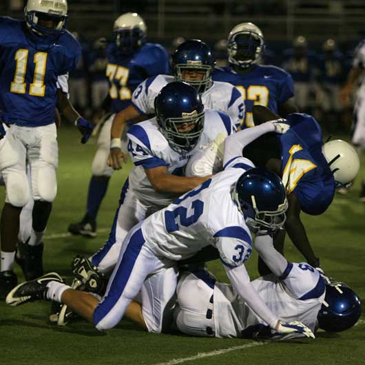 Aronn Bell (8), Stoney Stevens (32), and Jared Koon (44) haul down North Little Rock's Altee Tenpenny. (Photo by Rick Nation)