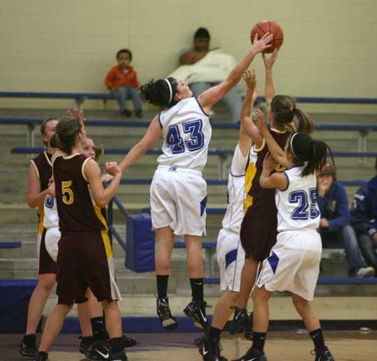 Bryant's Courtney Davidson (43) leaps high to block a shot as a pair of teammates including Carley Yazza (25) help defend. (Photo by Rick Nation)