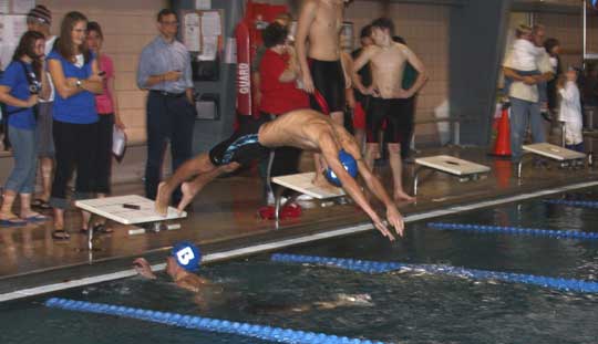 Jordan Combs dives in as Kyle Douglas touches during Friday's 400 freestyle relay at El Dorado.