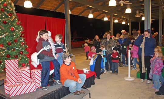 Austin, Aaron and Andrew Cook pose for a photo with Santa Claus as many other children wait in line for their turns.