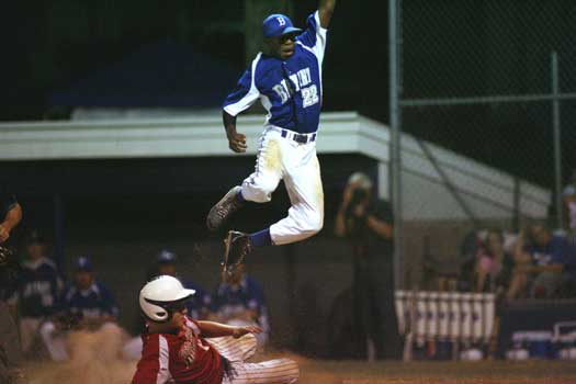 Pitcher Marcus Wilson leaps hit to try to flag down a wild throw as White Hall's Clay Cannon scores. (Photo by Rick Nation)