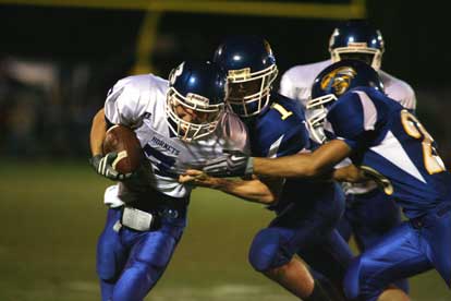 Chris Arnold, left, tries to break through the tackle of Sheridan's Cameron Holland (1) and Austin McClure (20). (Photo by Rick Nation)