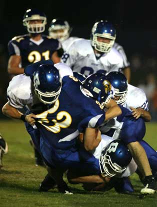 A trio of Hornets defenders drive Sheridan runner Alden Fletcher to the ground. (Photo by Rick Nation)