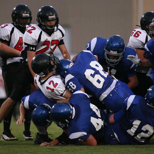 A swarm of Hornets led by Tyler Hayden (68), Jared Koon (44) and Ian Shuttleworth (12) pile up Searcy's quarterback during Bryant's season-opening win. (Photo by Rick Nation)