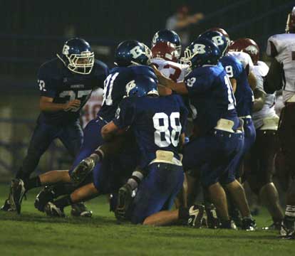 Hornet defenders Ryan Cox (91), Blake Heil (88), Hunter Mayall (18), and Stanley Oxner (19) stack up Texarkana running back Rod Rose as Trey Sowell (37) arrives to help out. (Photo by Rick Naiton)