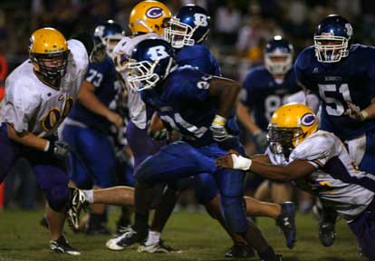 Chris Rycraw (21) cuts upfield off a block from Kaleb Burns (51) as Catholic's Stacy Hunter (84) tries to hang on. (Photo by Rick Nation)