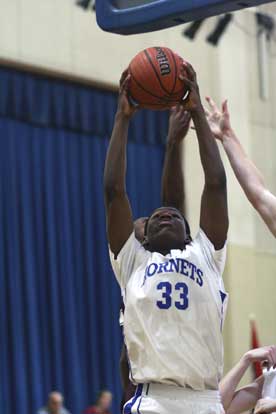 Leon Neale goes high in traffic to claim a rebound for the Bryant Hornets Monday night. (Photo by Rick Nation)