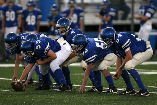 Bryant Blue quarterback Brandon Warner (4) prepares to start a play behind linemen Brittan Crouch (54), Nic Jenkins (55), Zach McConnell (59). (Photo by Kevin Nagle)