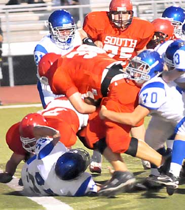 Bryant's Tanner Rich (70) and Ashton Henry (55) try to bring down Cabot fullback Keith Pledger (38). (Photo by Kevin Nagle)