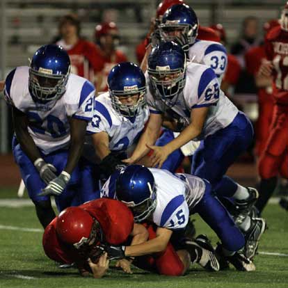 Jacob Irby (15) makes a tackle as Greyson Giles (20), Davis Nossaman (23) and James Gibson (65) arrive to help. (Photo by Rick Nation)