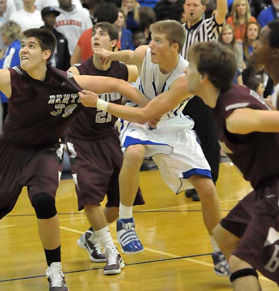 It was a tug-o-war at the Hornets Nest Tuesday. Here, Benton's Graham Gardner, left, and Bryant's Quinton Motto grapple in front of Benton's Tyler Gattin (21) under the boards. (Photo by Kevin Nagle)