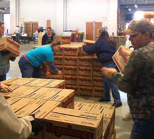 Volunteers stack the boxes of Girl Scout Cookies that have arrived at Saline County Armory. 