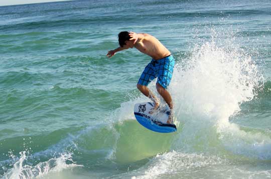 Jimi Easterling catches a wave during a little recreation time for the Bryant Hornets baseball team at Destin, Fla. (Photo by Phil Pickett)