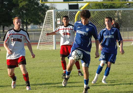 Bryant's Peter Alverio advances the ball ahead of a pair of Cabot defenders and teammate Cameron Furton. (Photo by Mark Hart)