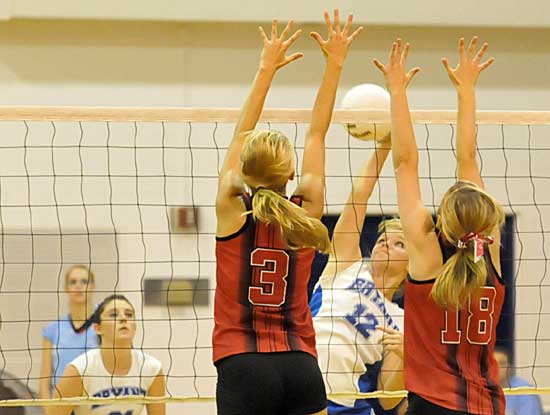 McKenzie Rice (12) tries to hit over a pair of Russellville blockers as Courtney Davidson, left, gets into position. (Photo by Kevin Nagle)