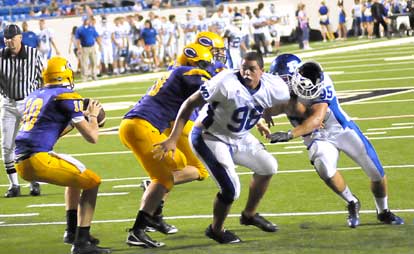 Bryant's Josh Hampton loses his helmet but continues to pursue quarterback Zach Conque along with teammate James Kidd (92). (Photo by Kevin Nagle)
