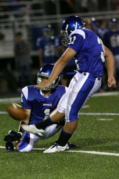 Alex Denker kicks an extra point out of the hold of Ty Harris. (Photo by Rick Nation)