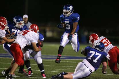 Karon Dismuke (5) leaps through a hole provided by Ian Shuttleworth (77), Cortez Williams (75) and Jordan Jones (79). (Photo by Rick Nation)