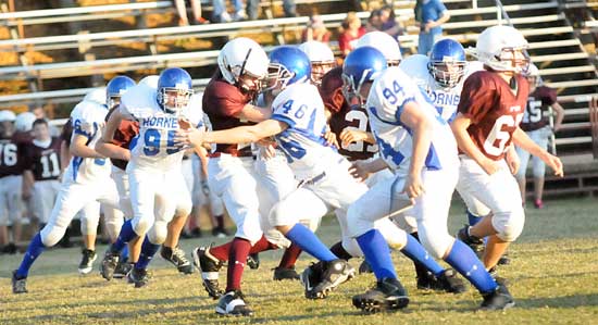 Drew Carnahan (46) makes a tackle as teammates Daniel Coppock (94) and Austin Blacklaw (95) among others close in. (Photo by Kevin Nagle)