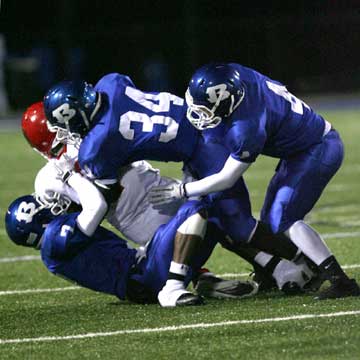 Aaron Bell (7), Walter Dunn (34) and Jesse Johnson (4) make a tackle. (Photo by Rick Nation)