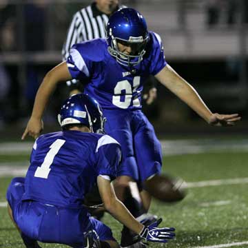 Alex Denker boots an extra point out of the hold of Ty Harris. (Photo by Rick Nation)