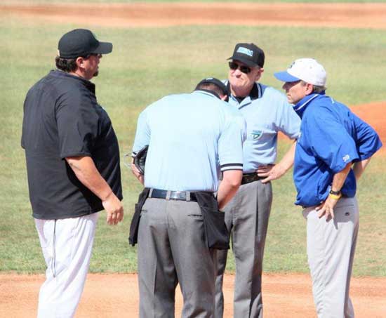 Bryant coach Kirk Bock, right, and East Ridge coach Darryl Blackall visit with the umpires at the pregame meeting at home plate.