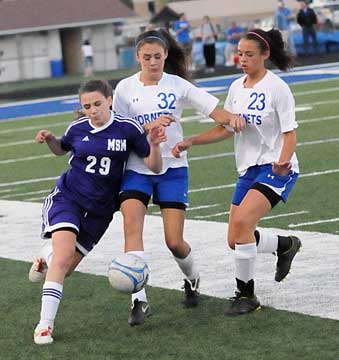 Rori Whittaker (32) and McKenzie Adams (23) crowd a Belles' player. (Photo by Kevin Nagle)