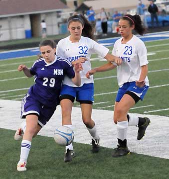 Rori Whittaker (32) and McKenzie Adams (23) crowd a Belles' player. (Photo by Kevin Nagle)
