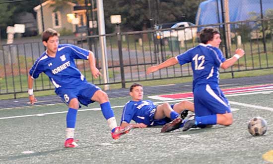 Ben Stukenborg, left, unleashes a free kick as Ryan Watson, middle, and Bryce Denker recover from their "collision" on a trick play that led to a goal by Alex Rowlan early in Tuesday's game at Conway. (Photo by Kevin Nagle)