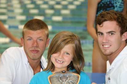 Coaches Kyle Douglas, left, and Jacob Wright, right, present Shelby Bratton with her award at the Meet of Champs.