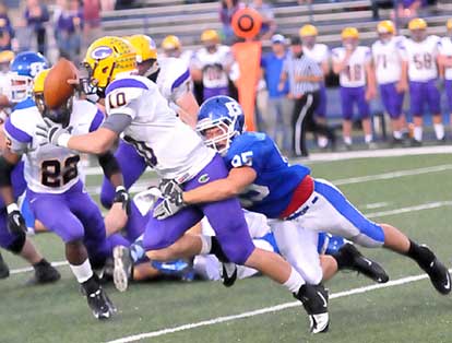 Michael Smith grabs Catholic quarterback Zach Conque. (Photo by Kevin Nagle)