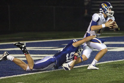Justin Hollingshead tries to bring down Sheridan quarterback Dylan Flores. (Photo by Rick Nation)