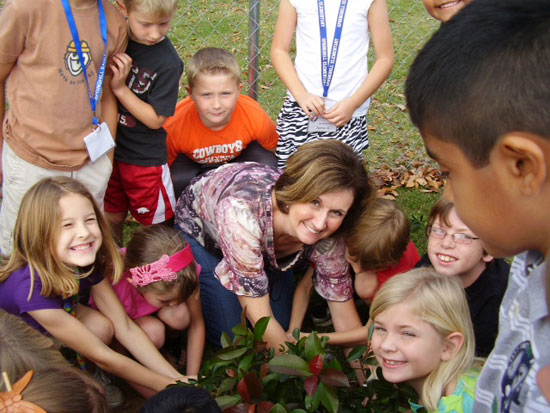 Second grader students help plant flowers and shrubs.