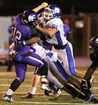 Tim Kelly (91) and Kordell Boykins hit El Dorado quarterback Lucas Reed just after he releases a pass. (Photo by Rick Nation)