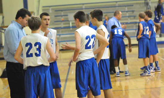 Bryant White coach Heath Long meets with his team while Bryant Blue coach Derek McGrew, right, meets with his during a timeout in Monday night's seventh grade game. (PHoto by Kevin Nagle)