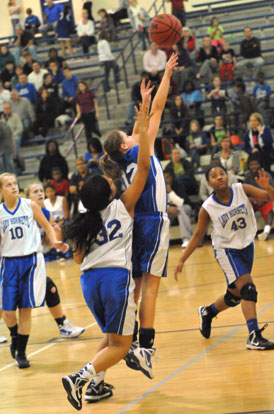 Bryant Blue's Sarah Kennedy (12) releases a shot in front of Bryant White's Kennedy Harris (32) and Deja Rayford (43). (Photo by Kevin Nagle)