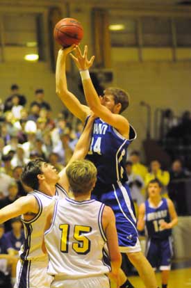Catholic's Matt Morris puts a hand in the face of Bryant's Quinton Motto who was still able to make the shot. (Photo by Kevin Nagle)