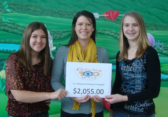 Elizabeth Palmer, left, and Riley Hill, right, present a check to Jill McIlroy of the Arkansas Children's Hospital Foundation.