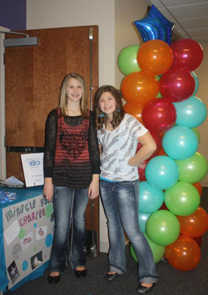 Riley Hill and Elizabeth Palmer in front of the donation table set up at their birthday party at The Center at Bishop Park.