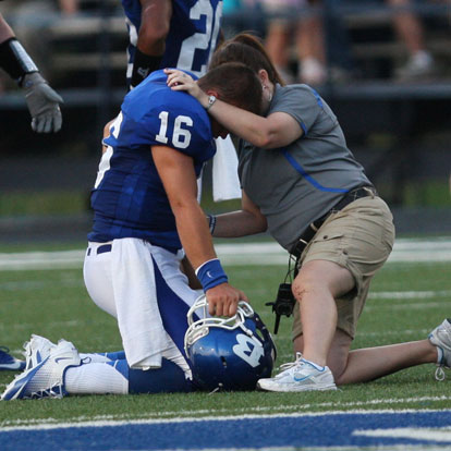 Quarterback Hayden Lessenberry (16) is tended to by trainer Christa Finney after getting shaken up early in Friday's game. (Photo by Rick Nation)