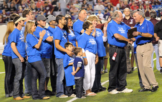 Bob Padgett, surrounded by his family, is handed the Community Support Award by Bryant athletic director Mike Lee at halftime of Friday night's Salt Bowl. (Photo by Kevin Nagle)