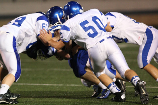 Austin Blacklaw (69), Austin Fason (50) and Nick Gatlin (57) join Walker Brown (obscured) in a sack of Conway White quarterback Greyson Pinkston. (Photo by Rick Nation)