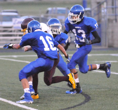 Nick Hardin (16) and Jaelyn Jones (13) join a teammate on a tackle. (Photo by Kevin Nagle)