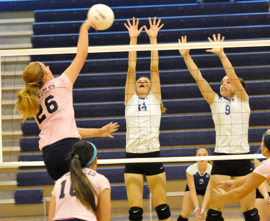 Seirra Jones (14) and Kendall Selig (9) try to block a Rogers Heritage hit. (Photo by Kevin Nagle)