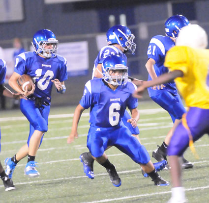 Sarah Evans (6), Parker Littleton (22) and Luke Curtis (21) lead Mike Jones (10) on a kickoff return during Tuesday's game. (Photo by Kevin Nagle)