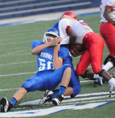 Aaron Eley (50) hangs on, trying to bring down McClellan's Pierce Strong. (Photo by Kevin Nagle)