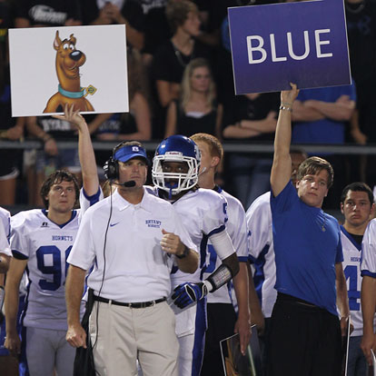 Bryant head coach Paul Calley looks on as volunteer assistant Robbie Aldredge, right, and a Hornet player use the team's variety of signs to call in plays. (Photo by Rick Nation)