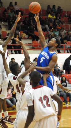 K.J. Hill (5) goes high for a shot over taller Texarkana defenders inside. (Photo by Kevin Nagle)